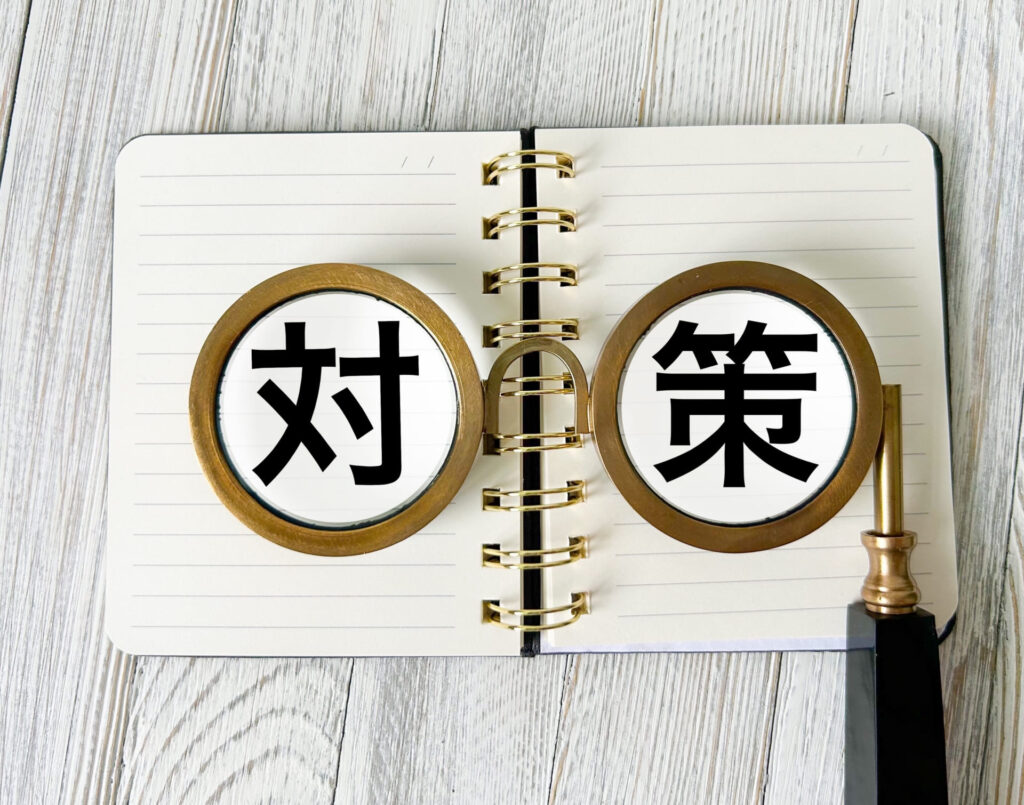ノートの上に置かれた虫眼鏡に「対」「策」の漢字が映っている様子。